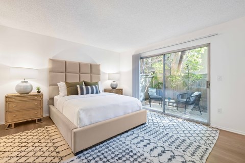 a bedroom with a large bed and a sliding glass door overlooking a private patio